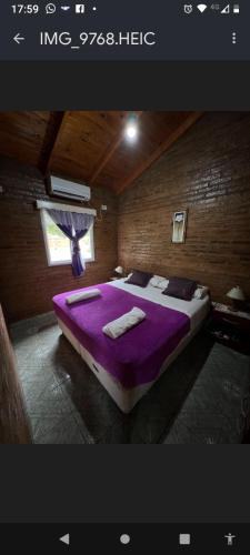 a bedroom with a bed with purple sheets and a window at Mi Buen Refugio in Puerto Iguazú