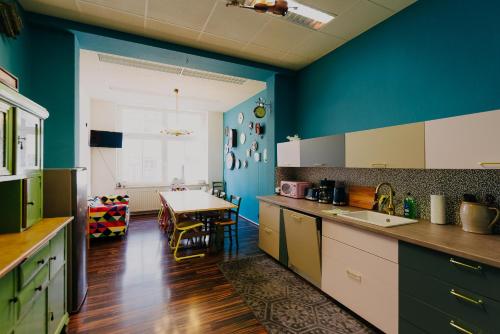 a kitchen with blue walls and a dining room with a table at LaLeLu Hostel Dresden in Dresden