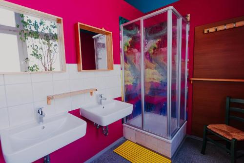 ein rosafarbenes Bad mit einem Waschbecken und einer Dusche in der Unterkunft LaLeLu Hostel Dresden in Dresden