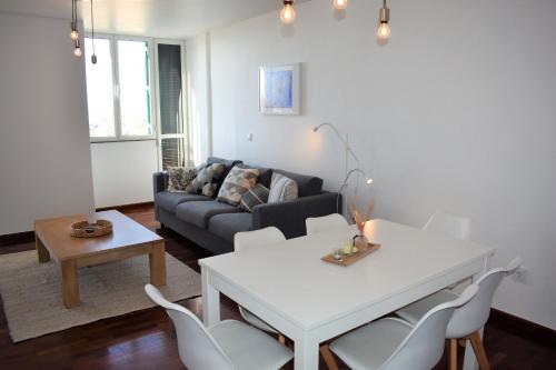 uma sala de estar com um sofá, uma mesa e cadeiras em Madeira, 3 bedroom apartment with ocean views in Funchal em Funchal