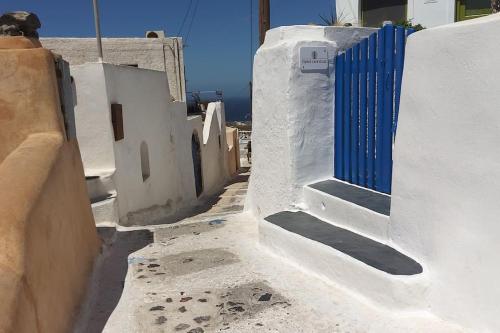 an alley with white buildings and a blue door at Finikas Cave House in Foinikiá