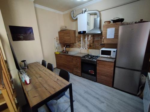 a kitchen with a wooden table and a refrigerator at Wooden_Room_Hostel in Yerevan