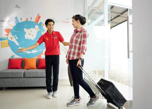 a man and a woman pulling a suitcase at Central Front One Inn Jakarta Airport in Rawabokor Dua