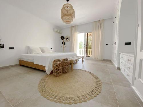 a white bedroom with a bed and a rug at Celebrate Life's Precious Moments at Can Saca! in Sant Jordi