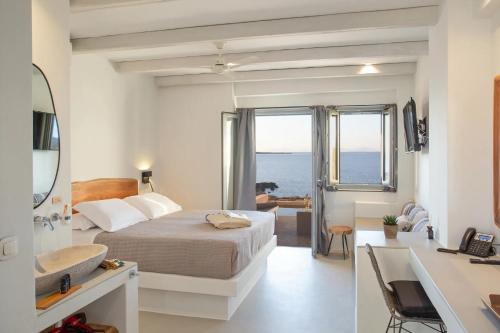 a bedroom with a bed and a sink and a bathroom at Paros Cape Suites in Naousa