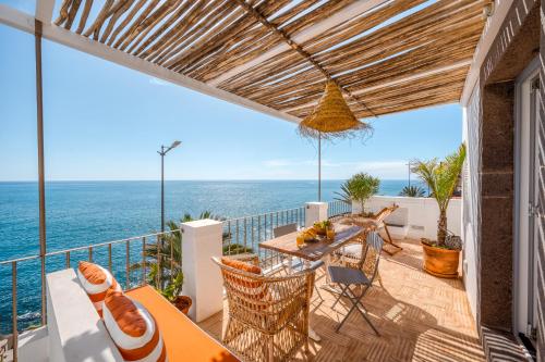 a balcony with a table and chairs and the ocean at Casa da Rocha in Câmara de Lobos