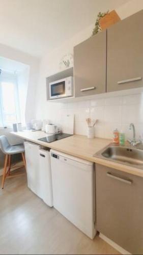 une cuisine avec un évier et un plan de travail dans l'établissement Appartement avec piscine, 100m plage et hypercentre, à Cabourg