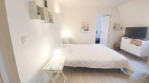 Dormitorio blanco con cama y mesa en Appartement avec piscine, 100m plage et hypercentre en Cabourg