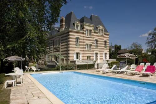 une grande maison avec une piscine en face de celle-ci dans l'établissement Appartement avec piscine, 100m plage et hypercentre, à Cabourg