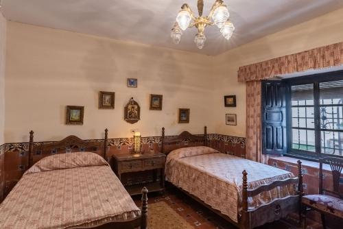 a bedroom with two beds and a chandelier at Finca casa rural de la Mata in Toledo