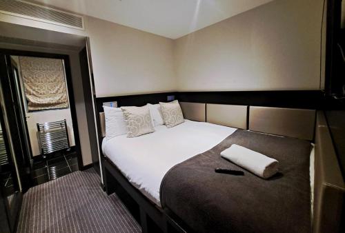 een slaapkamer met een groot bed met witte lakens en kussens bij Great St Helen Hotel in Londen