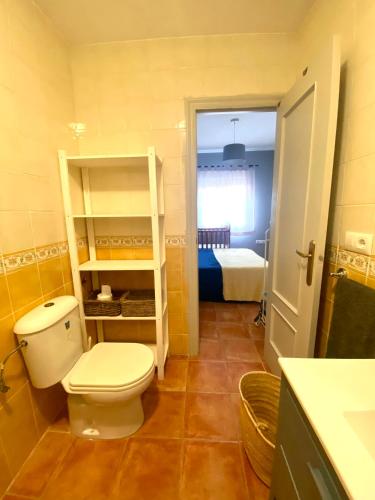 a bathroom with a toilet and a room with a bed at Ático Islantilla Golf in Islantilla