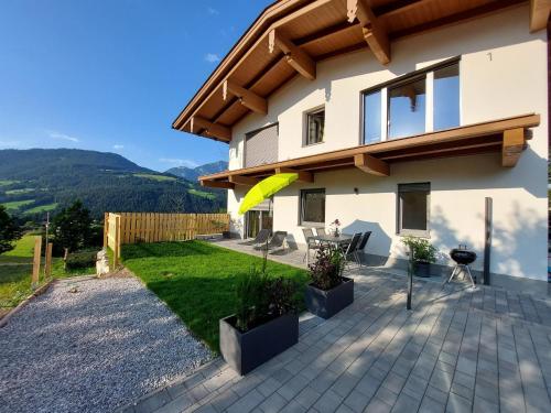 a house with a patio with a yellow umbrella at Ferienwohnung Pölvenblick in Söll