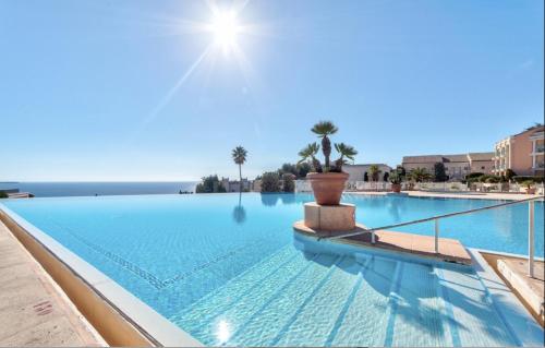 une grande piscine avec de l'eau bleue et des palmiers dans l'établissement Appt Vue Mer Exceptionnelle sur baie de Cannes, à Cannes