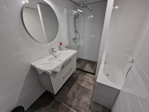 a white bathroom with a sink and a mirror at Woonhotel Petruskerk in Vlissingen