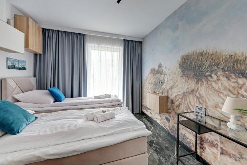 グダニスクにあるWAVE APARTMENTS-GOLD EXCLUSIVEの壁に絵画が飾られた部屋のベッド2台