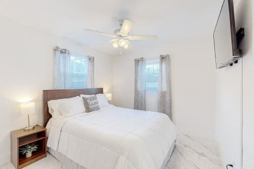 um quarto branco com uma cama e uma ventoinha de tecto em Seaview Suite em Deerfield Beach