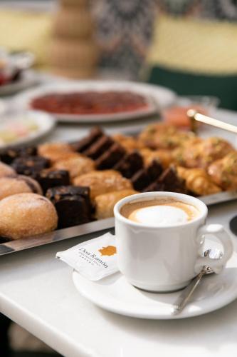 a table with a cup of coffee and a tray of donuts at Hotel Casa Palacio Don Ramón in Seville
