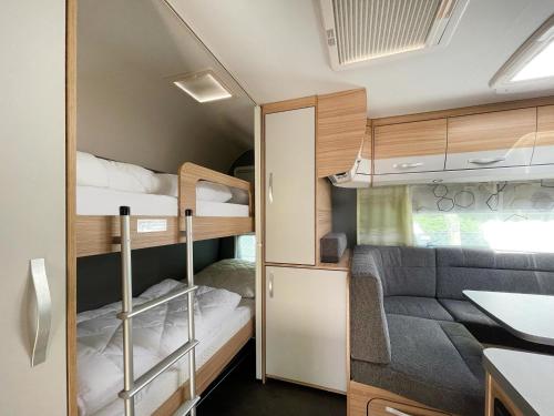 mały pokój z 2 łóżkami piętrowymi i kanapą w obiekcie Mietwohnwagen 01 w mieście Heringsdorf