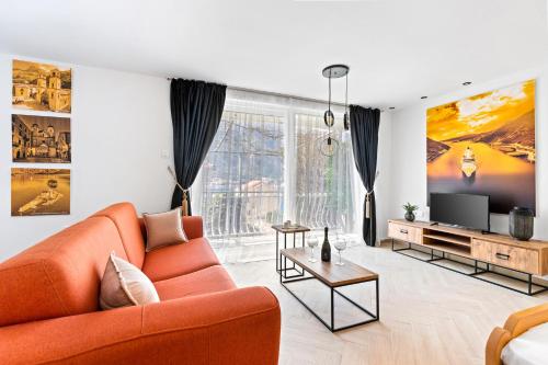 een woonkamer met een oranje bank en een tv bij Apartments Casa Mia in Kotor