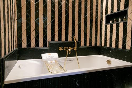 a bath tub with a gold faucet in a bathroom at Hotel Casa Palacio Don Ramón in Seville