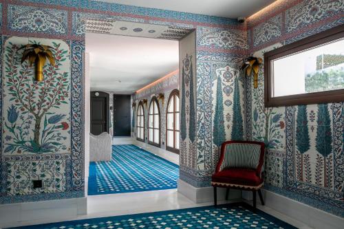 a hallway with blue and white wallpaper and a red chair at Hotel Casa Palacio Don Ramón in Seville