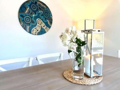 a vase of flowers on a table with a plate at Blairgowrie Beach what a spot Relax in private in Blairgowrie