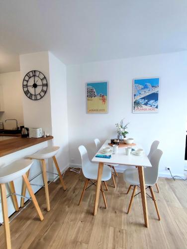 une salle à manger avec une table, des chaises et une horloge dans l'établissement GRAND VOILE - Hyper centre, Climatisation, Vue panoramique sur l'architecture de La Grande Motte, à La Grande Motte