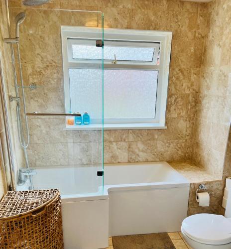a bathroom with a tub and a toilet and a window at Reading West Homestay in Reading