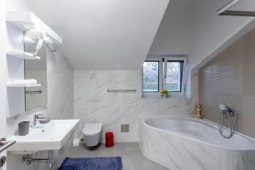 een witte badkamer met een bad en een wastafel bij Rtina Appartements in Rtina