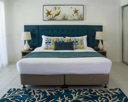 a large bed with a blue headboard and two lamps at 1770 Lagoons Central Apartment Resort in Agnes Water