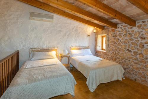 duas camas num quarto com uma parede de pedra em Villa Petita Llombards em Llombarts