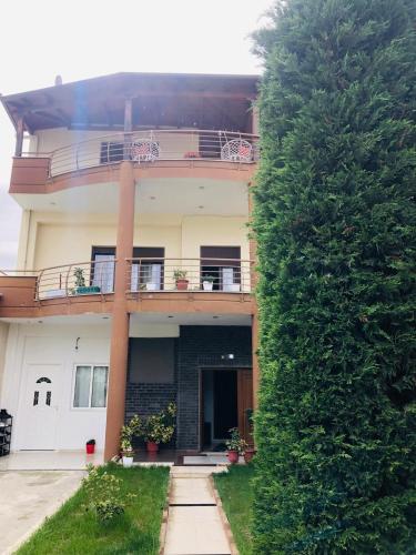 un bâtiment avec un grand arbre vert devant lui dans l'établissement Villa 1 Uklala, à Kamëz