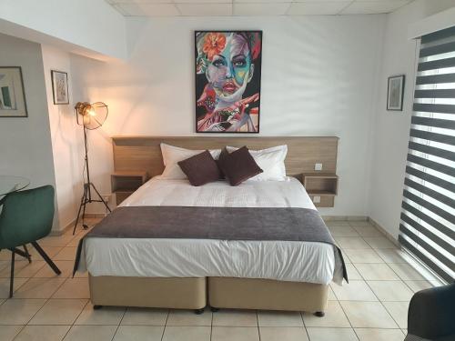 a bedroom with a bed with a painting on the wall at Larnaca Bay Suites in Larnaka