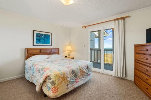 Schlafzimmer mit einem Bett, einem TV und einem Fenster in der Unterkunft High Dunes in Kill Devil Hills