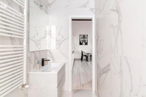 een badkamer met witte marmeren muren en een wastafel bij Pop Art Loft con Giardino Privato in Busto Arsizio