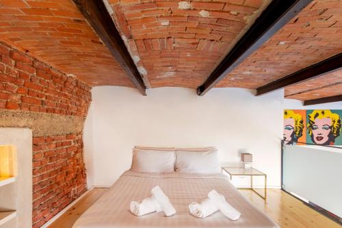 Cama en habitación con pared de ladrillo en Pop Art Loft con Giardino Privato, en Busto Arsizio