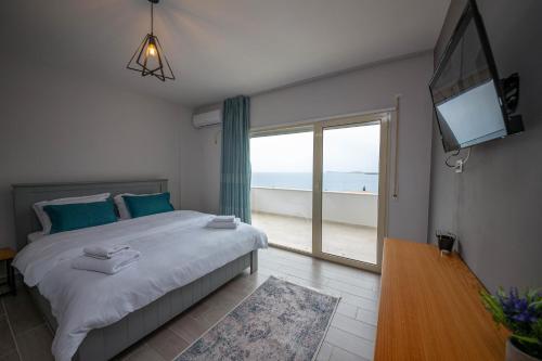 a bedroom with a large bed and a large window at Aerial Hotel & Spa in Vlorë