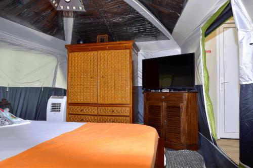 - une chambre avec un lit et une commode avec une télévision dans l'établissement Redoute Paradise, à Fort-de-France