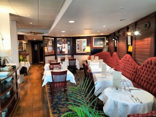 un restaurante con mesas blancas y sillas rojas en Logis HOTEL RESTAURANT La Régence en Cherbourg en Cotentin