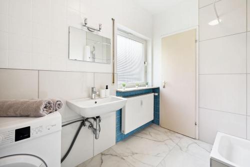 a white bathroom with a sink and a washing machine at Monteurwohnungen am Neckar in Köngen