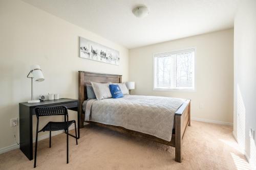 een slaapkamer met een bed en een bureau met een stoel bij New 3BR Townhouse, Minutes to Niagara Falls and Brock University by GLOBALSTAY in Thorold