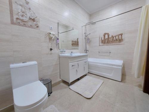 a bathroom with a toilet and a sink and a tub at Hotel Times in Bukhara