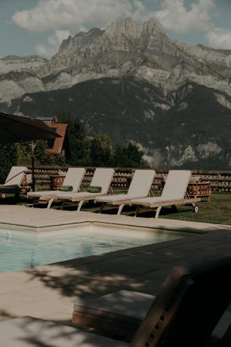 a group of lounge chairs sitting next to a swimming pool at Hôtel Les Roches Fleuries in Cordon