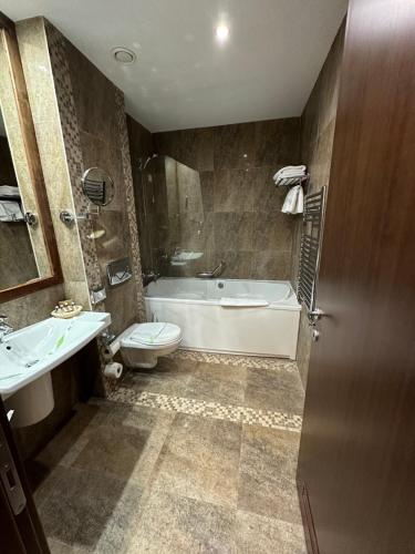 ein Badezimmer mit einer Badewanne, einem WC und einem Waschbecken in der Unterkunft Hotel Alpin Aparthotel Apartament 301 in Poiana Brașov