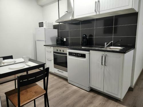 a kitchen with white cabinets and a sink and a stove at O Abel Hotel rural in Bragança