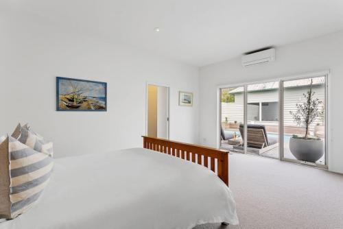 a white bedroom with a large bed and a window at Coastal Cool -Pool, Tennis Court in Sorrento