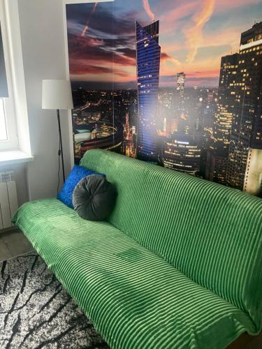 a green couch in a room with a view of a city at Komfort na Tamce,parter, niedaleko starówki, Powiśle in Warsaw