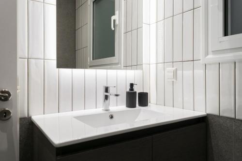 Un baño con un lavabo blanco y un espejo. en Callirhoē Luxury 2BD Acropolis Apartment, en Atenas