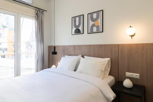 Un dormitorio con una cama blanca y una ventana. en Callirhoē Luxury 2BD Acropolis Apartment, en Atenas